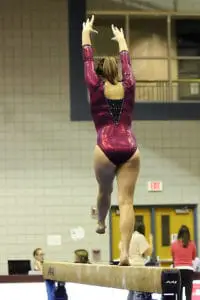 Gymnast performing kick on beam